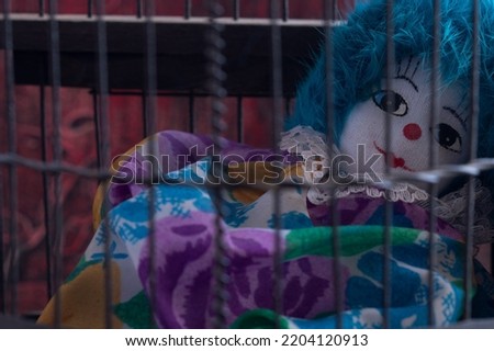 Clown in prison concept of man behind bars. Creative decoration of a prison interior. Locked art concept.
