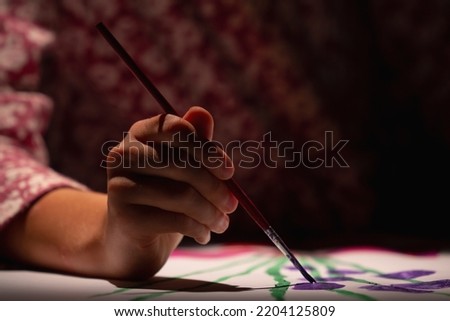 Happy young girl painting in at her home. Selective focus on hand.