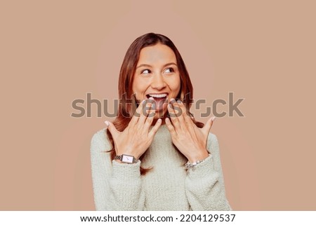 Close up portrait of young mixed race brunette woman with curly hair, wears green sweater, posing at studio with happy surprise facial expression over beige wall background. Female student. Royalty-Free Stock Photo #2204129537