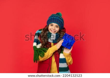 cheerful child in winter clothes hold box on red background, boxing day