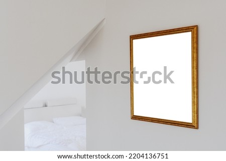 Empty mockup copy space in gold colored wooden picture frame hanging on the bedroom wall, selective focus