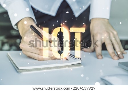 Double exposure of creative IOT hologram with hand writing in notebook on background with laptop, research and development concept
