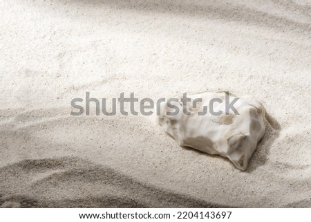 Natural cosmetic background for product presentation. White stone on the sand. Front view.