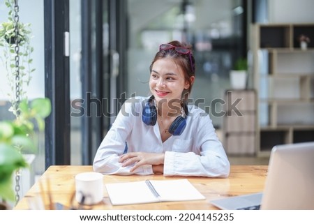 woman showing a smiling face and using a computer and notebook to work