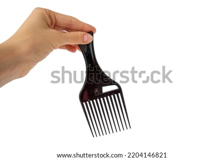 Afro Hair Pick, AfroPick black hair comb curly in a woman's hand on an isolated white background.