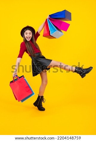 Funny teen girl hold shopping bag enjoying sale isolated on yellow. Portrait of teenager schoolgirl is ready to go shopping. Run and jump. Excited teenager, glad amazed and overjoyed emotions.
