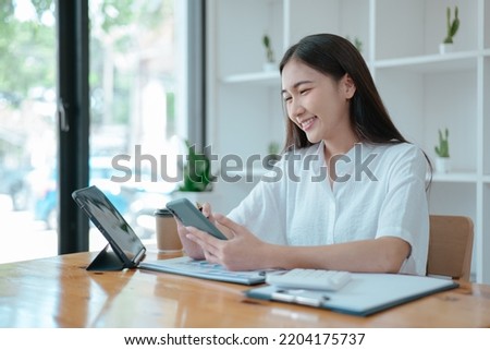 Businesswoman working on tablet and laptop in office with happy face.
