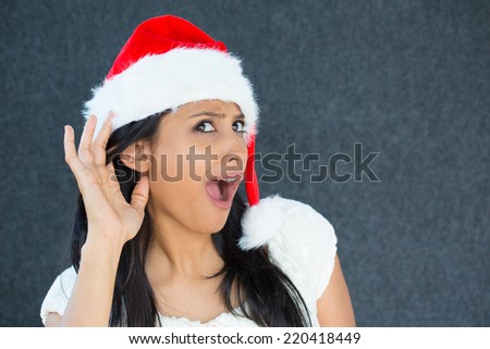 Closeup portrait of a cute Christmas woman with a red Santa Claus hat, white dress, eavesdropping,happy surprise, wide-open mouth, looking up.Positive human emotion on isolated grey background.