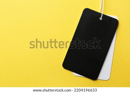 Tags with space for text on yellow background, top view