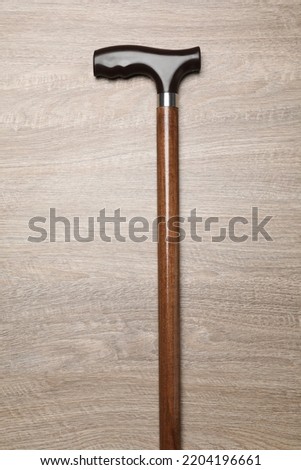 Elegant walking cane on wooden table, top view
