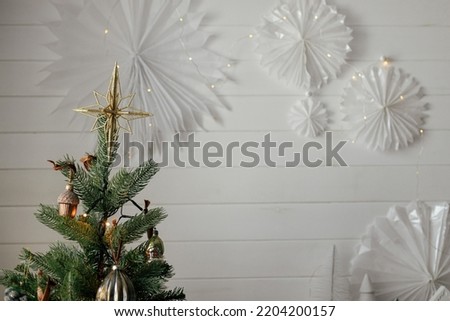Christmas tree with vintage star on top and golden lights. Modern decorated christmas tree branches with stylish ornaments close up in festive room. Winter holidays, atmospheric time