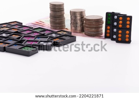 Black dominoes and stacks of coins line the financial situation in an economic crisis concept.