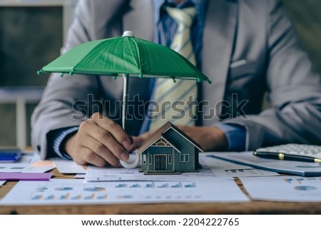 Home and real estate insurance ideas, individuals holding small umbrellas and sample homes. Home insurance for upcoming losses and fires building fire insurance Royalty-Free Stock Photo #2204222765