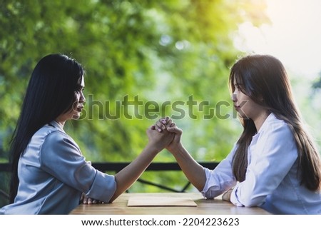 Businesswomen shaking hands with business competitors, Arm wrestling challenge between competing with colleagues and foes.