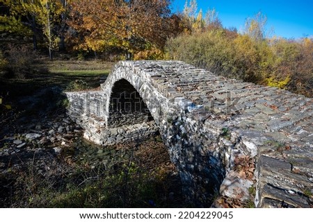 View of the traditional stone Agiou MIna Bridge in Epirus, Greece in Autumn
