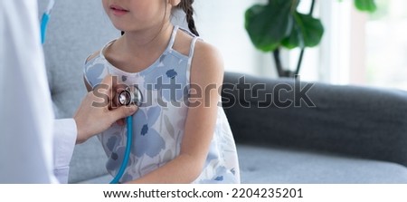 Asian woman pediatrician doctor hold stethoscope for exam a little girl patient and heck heart lungs of kid, Good family doctor visiting child at home, Healthcare and medicine for childhood concept. Royalty-Free Stock Photo #2204235201