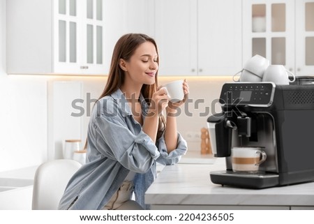 Young woman enjoying fresh aromatic coffee near modern machine in kitchen Royalty-Free Stock Photo #2204236505