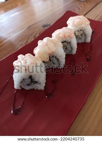 tuna and nori roll sushi in the red plate on the wooden table. With spicy sauce.