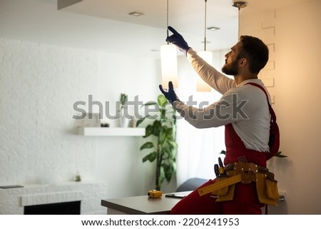 electrician installing led light bulbs in ceiling lamp Royalty-Free Stock Photo #2204241953