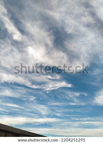 white blurry clouds across the blue sky