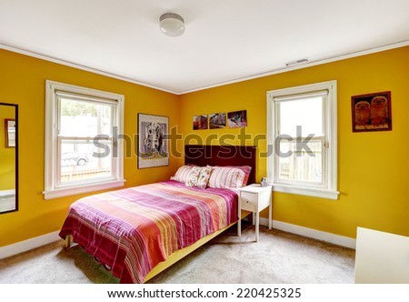 Bedroom in bright yellow color with single bed. Red stripped bedding
