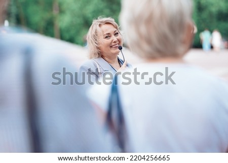 female tour guide with a microphone standing among a group of tourists. Royalty-Free Stock Photo #2204256665