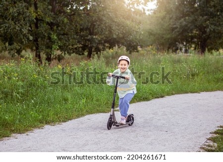 portrait of cute  little caucasian school girl wear helmet enjoy having fun riding  scooter on  asphalted track
in street park outdoors on sunny day. Healthy sport children activities outsid Royalty-Free Stock Photo #2204261671