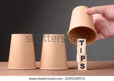 Man playing three cups shell game and reveal the right position where the TIPS is