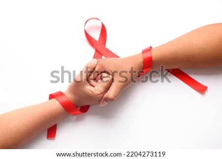 Two hands holds each other with red ribbon. Aids day concept