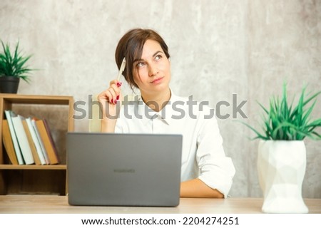 A thoughtful, worried European student worker who feels insecure, bored, doubtful about solving a problem at work with a laptop, a puzzled businesswoman looking away, thinking that she has no idea Royalty-Free Stock Photo #2204274251
