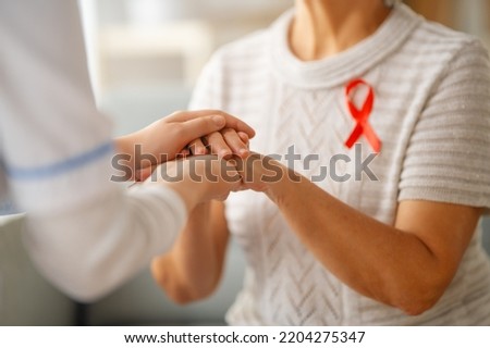 Pink ribbon for breast cancer awareness. Female patient listening to doctor in medical office. Support people living with tumor illness. Royalty-Free Stock Photo #2204275347