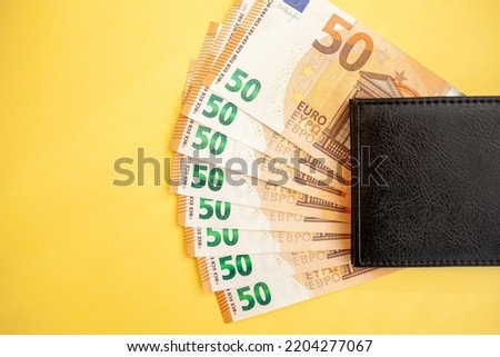 Fifty euro banknotes inside a black wallet on yellow background, cash paper currency, payment, earning and savings, european currency, money and finance concept