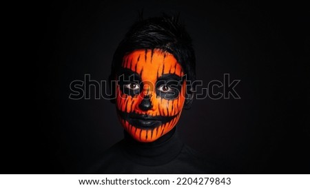 Halloween or horror concept child boy. Studio shot over black background. The Day of the Dead. Scary little boy smiling in halloween makeup.