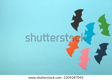  colorful bats on the right side of a blue background, next to copy space, flat lay, craft paper