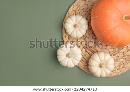 Autumn composition. Various pumpkins on olive green Background. Flat lay, top view, copy space. Nordic, hygge, cozy home concept. Thanksgiving fall decoration. Halloween Modern Invitation Mock up