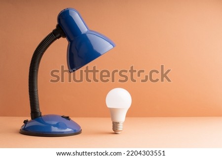 led light bulb on table and lamp. idea while working, a light bulb as a symbol of a new topic