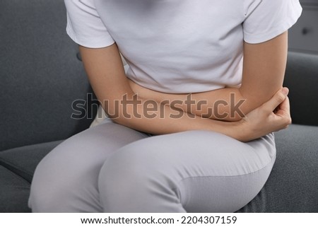 Woman suffering from cystitis on sofa at home, closeup Royalty-Free Stock Photo #2204307159