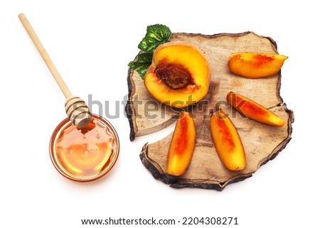 Peach slices on a wooden board and honey with a wooden spoon. Shallow depth of field