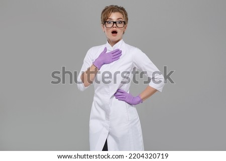 Woman doctor in white coat emotionally surprised isolated on gray background.