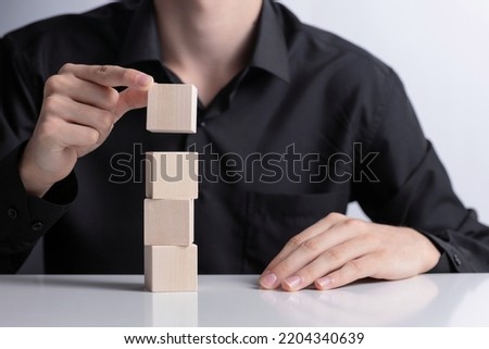 Man's hand completing set of 4 stacked wooden cubes., man build a tower by using four blank wooden cube on table. Mockup for letters, symbol, picture text, word, idea and concept.