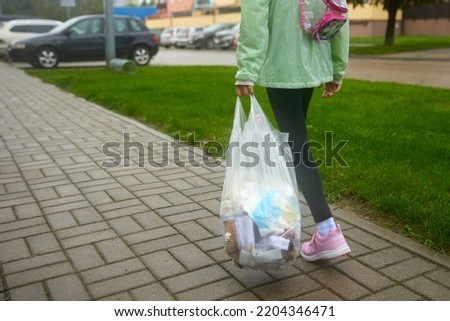 Black garbage in the children hand stand on road on green background Royalty-Free Stock Photo #2204346471