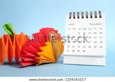 Hello November 2022 with Thanksgiving Day concept. Desk calendar with turkey and pumpkin paper craft on blue background.
