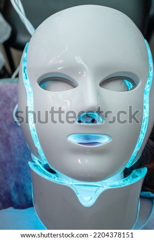 A red LED face masque on a caucasian lady in a spa. Royalty-Free Stock Photo #2204378151