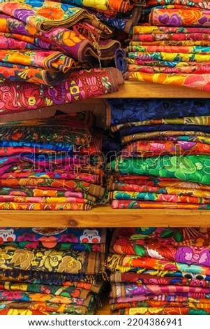 Brightly colored handwoven textiles stacked on a wooden shelf in Merida, Mexico Royalty-Free Stock Photo #2204386941