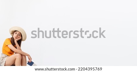 Lifestyle and travel Concept: Young beautiful caucasian woman is sitting on suitecase and waiting for her flight.Isolated over white background