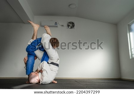 Brazilian jiu jitsu bjj training or sparing two athletes fighters dill martial arts technique at gym on the tatami mats wear kimono gi black belt instructor demonstrate submission armbar juji gatame Royalty-Free Stock Photo #2204397299