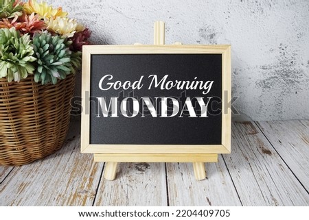 Good Morning Monday text message on easel blackboard standing on wooden background