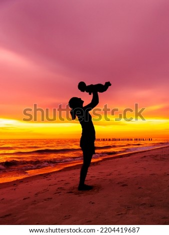 Beach sunset with silhouette of baby mom mother with ocean water background