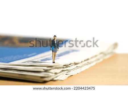 Miniature people toy figure photography. A businesswoman standing walking with newspaper on the desk. Isolated on white background. Image photo