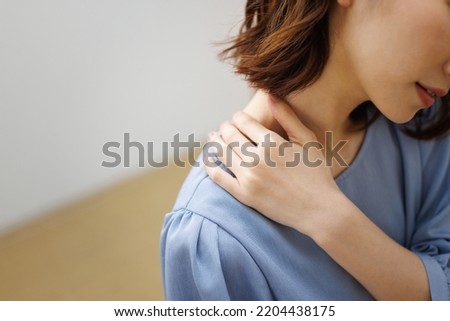 Image of a woman with stiff shoulders Royalty-Free Stock Photo #2204438175